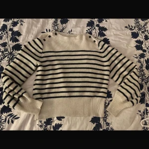 Randig stickad tröja med knappar - Läs info!💕Säljer en superfin randig stickad tröja i vitt och svart. Den har långa ärmar och coola knappar på axlarna som ger en extra touch. Perfekt för höst och vinter. Ena knappen håller på att ramla av men går att sy ! Köpt dyrt på Lindex 