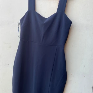Mörkblå klänning med slits - Snygg svart klänning med breda axelband och en elegant slits framtill. Perfekt för festliga tillfällen eller en kväll ute. Klänningen har en stilren design och är i ett bekvämt material som ger en smickrande passform.