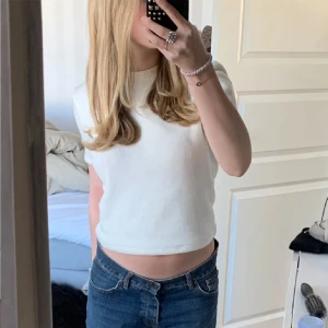 Vit croppad t-shirt - Säljer en superfin vit croppad t-shirt som är perfekt för sommaren. Den är kortärmad och har en enkel, stilren design. Passar perfekt till ett par jeans eller shorts för en avslappnad look.