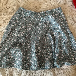 Blommig kjol från FB Sister - Säljer en superfin blommig kjol från FB Sister i storlek S. Köpt på New Yorker. Kjolen har en härlig grön färg med vita blommor och är perfekt för vår och sommar. Den är i bra skick och har en bekväm passform. Perfekt för en dag på stan eller en sommarfest! 🌸