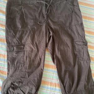 Bruna cargopants från XLNT Woman - Säljer ett par bruna cargopants från XLNT Woman i storlek 48. Byxorna har flera praktiska fickor med knappar och en bekväm dragsko i midjan. Perfekta för en avslappnad stil! saknas en knapp på ena bakfickan 