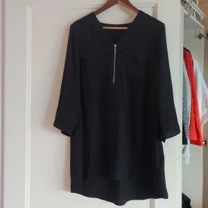 Svart klänning från Cellbes - Säljer en stilren svart klänning från Cellbes. Den har en dragkedja framtill och trekvartsärmar, vilket gör den perfekt för både vardag och fest. Klänningen är i ett mjukt och bekvämt material, vilket gör den skön att bära hela dagen.