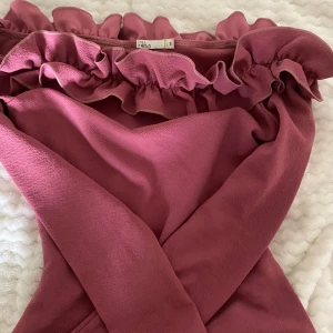 Rosa tröha från NLY Trend - Säljer en superfin rosa tröja från NLY Trend. Den har en söt volangdetalj upptill och är perfekt för sommarens fester. Klänningen är i storlek S och har en härlig, mjuk känsla.