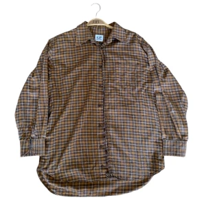 Brun och orange rutig skjorta från G.P. Bellini - Säljer en snygg brun och orange rutig skjorta från G.P. Bellini. Skjortan har långa ärmar och en klassisk krage. Perfekt för höst och vinter med sitt mysiga rutmönster. Den är i storlek L och passar perfekt för en avslappnad stil.