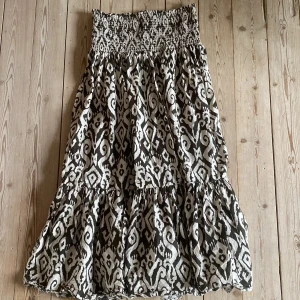 Mönstrad långkjol från Zara - Säljer en superfin långkjol från Zara med  mönster med svart och beige.En volangdetalj längst ner som ger extra flöde. Perfekt för sommar och vår, använt 1-5 gånger. Jag är 175 cm  men den är för kort för mig. storlek m