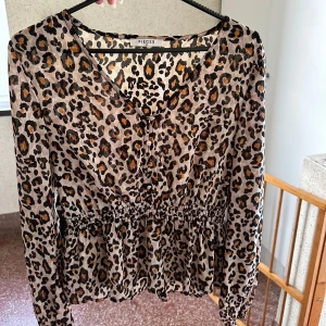 Leopardmönstrad blus från Pieces - Säljer en superfin leopardmönstrad blus från Pieces. Den har en v-ringad hals och långa ärmar. Blusen har en elastisk midja som ger en snygg passform. Perfekt för både vardag och fest!