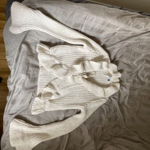 Vit ribbad kofta från Bershka - Säljer en superfin vit ribbad kofta från Bershka. Den har långa ärmar och en mysig passform, perfekt för kyliga dagar. Koftan är i nyskick och gjord av ett mjukt material som känns skönt mot huden. Perfekt att ha över en topp eller klänning för en stilren look!