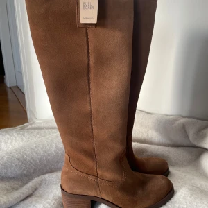 Bruna mockastövlar från Bullboxer - Snygga bruna stövlar i mocka från Bullboxer med dragkedja på sidan. Perfekta för höst och vinter med en stilren design och bekväm klack.