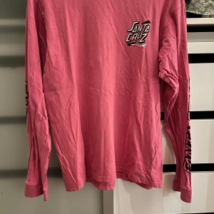 Rosa långärmad tröja från Santa Cruz - Säljer en cool rosa långärmad tröja från Santa Cruz. Den har tryck både fram och bak samt längs ärmarna. Perfekt för skate eller chill dagar. Tröjan är i bra skick och superbekväm. Passa på att köpa den nu! 💖