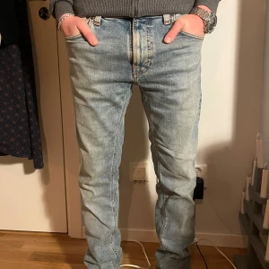 Ljusblå jeans från Nudie Jeans - Säljer ett par ljusblå jeans från Nudie Jeans i bra skick. De har en klassisk straight passform och är tillverkade i slitstarkt denim. Perfekta för både vardag och fest! 🕺