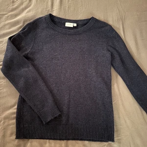 Marinblå stickad tröja - Säljer en snygg marinblå stickad tröja från Vila i storlek S. Perfekt för kyliga dagar med sin mjuka och bekväma passform. Tröjan har långa ärmar och ribbade kanter vid ärmslut och nederkant. Passar både till vardags och lite finare tillfällen. 🧶💙