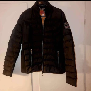 Svart pufferjacka från Parajumpers - Säljer en svart pufferjacka från Parajumpers med orange foder och dragkedja framtill. Jackan har en broderad logotyp på ärmen och är perfekt för kyligare väder. Den har långa ärmar och praktiska fickor med dragkedja. Finns ingen skador 🤝