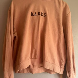 Beige hoodie från Divided - Säljer en beige hoodie från Divided med texten 'B.A.B.E.S' på framsidan. Tröjan har en klassisk design med huva och långa ärmar. Perfekt för en avslappnad stil. OBS! Varan finns på andra säljsidor också så skynda att fynda innan någon annan gör de!💕