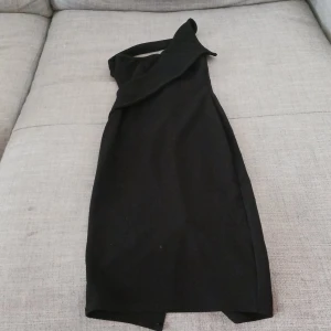 Svart klänning från PrettyLittleThing - Snygg svart klänning från PrettyLittleThing i storlek S. Den har en elegant oneshoulder-design och en smickrande passform. Perfekt för festliga tillfällen! 🖤