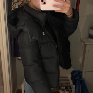 Svart dunjacka från Calvin Klein - Snygg svart dunjacka från Calvin Klein med dragkedja och huva. Perfekt för kyliga dagar, med en stilren design och praktiska fickor framtill. Jackan har en normal passform och är näst intill nyskick😇pris går att diskutera 