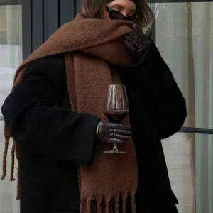 Brun halsduk - Snygg och stor brun halsduk som ger en mysig känsla. Perfekt för kyliga dagar och kan enkelt matchas med olika outfits. Den har en klassisk design med fransar i ändarna.