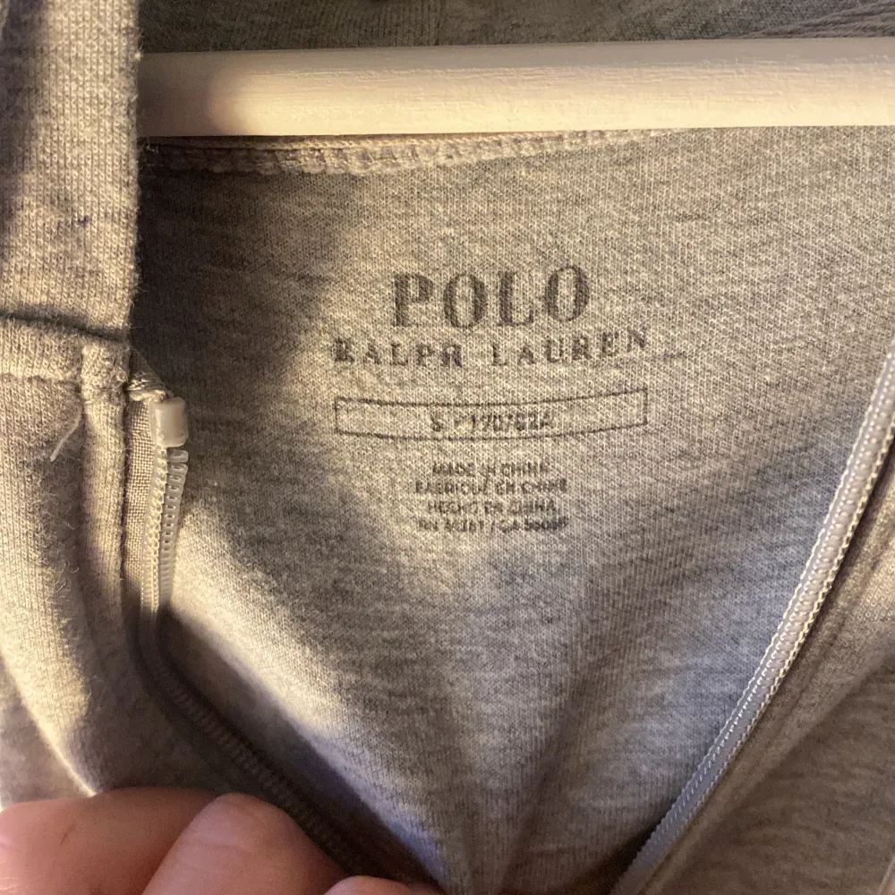 Säljer en stilren grå hoodie från Polo Ralph Lauren i storlek S. Den har en dragkedja framtill och en klassisk logga på bröstet. Perfekt för både höst och vår, och passar till vardags eller träning. Superbekväm och i bra skick!. Tröjor & Koftor.