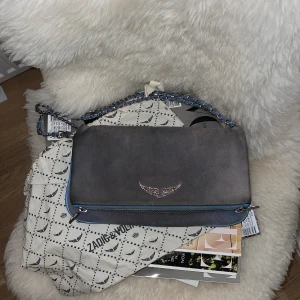 Grå axelväska från Zadig & Voltaire - Snygg grå axelväska i mocka från Zadig & Voltaire med en lång kedja som går att vika till en kort som jag gjort på bilden. Den är i bra skick ändast lite rost och kommer med en dustbag.❤️