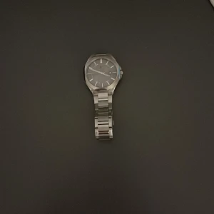 Silverfärgad klocka från Viktor Frisk x Guldfynd - Snygg och stilren klocka i silver från Viktor Frisk x Guldfynd. Klockan har en klassisk design med metallarmband och en rund urtavla. Perfekt för både vardag och fest! Kommer i originalförpackning.   Den passar perfekt för mig, och min handled är 17 cm. Nypris är 1400 kr.