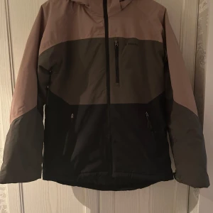 Flerfärgad jacka från Everest - Säljer en snygg flerfärgad jacka från Everest i storlek 170. Jackan har en cool design med dragkedja och flera praktiska fickor. Perfekt för höst och vinter med sin varma och tåliga polyesterkonstruktion. Den har långa ärmar och en huva för extra skydd mot väder och vind.