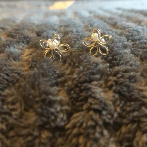 Örhängen med blomdesign - Säljer ett par superfina örhängen formade som blommor. De har en elegant design med små pärlor i mitten av varje blomma. Perfekta för att ge en touch av glamour till vilken outfit som helst. Passar både till vardags och fest! 🌼✨