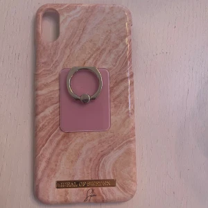 Rosa mobilskal till IPhone xs från Ideal Of Sweden.  - Rosa mobilskal från Ideal Of Sweden. Det är även en rosa mobilring/mobilhållare (borde gå att ta bort om det önskas). Ser ut som ny. Använd 1-2 gånger. Säljer pga köpte en annan mobil.