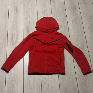 Röd Nike tech fleece - Säljer en röd Nike tech fleece, den är använd men växt ur den nu och skick är 8/10