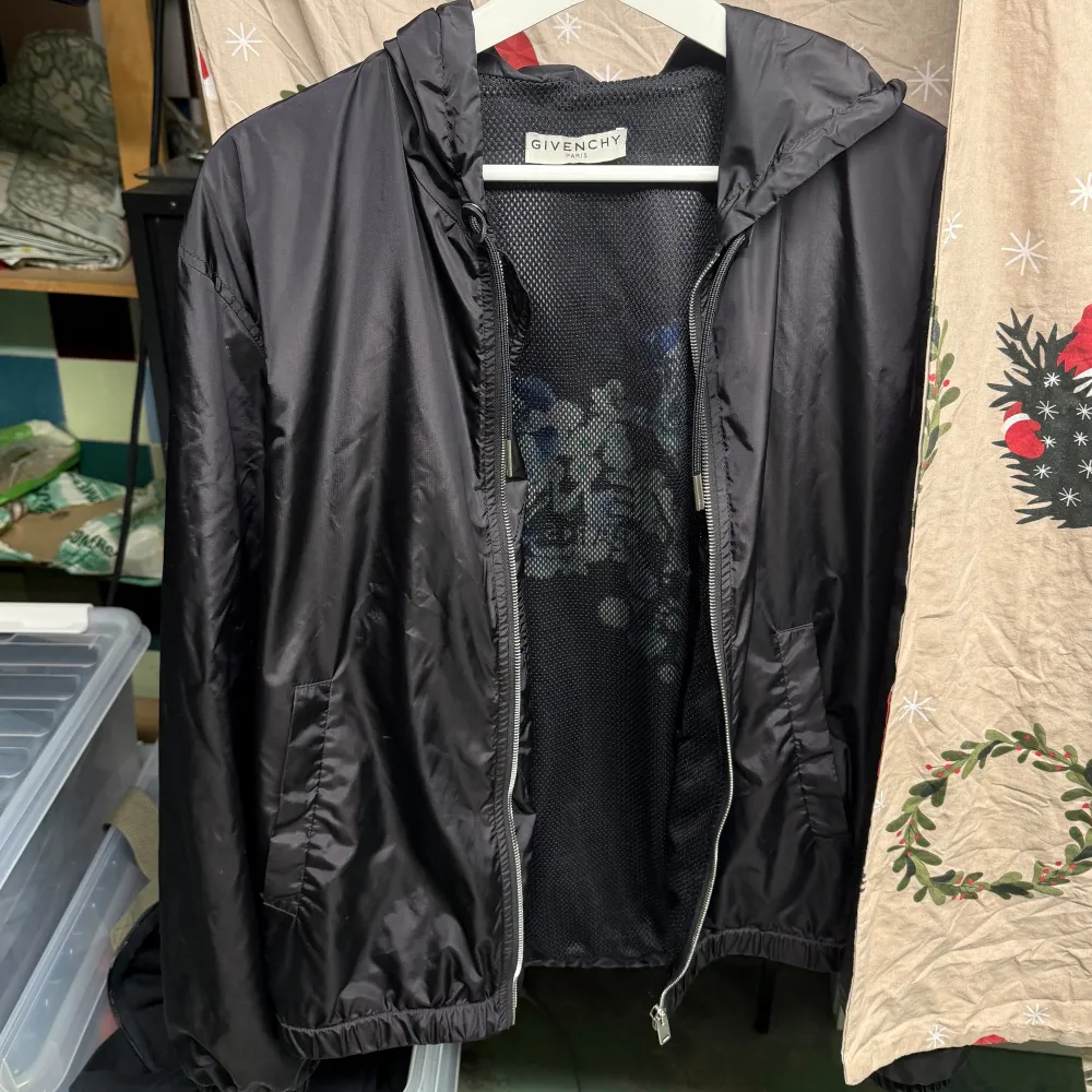 Säljer en snygg svart vindjacka från Givenchy. Jackan har en dragkedja framtill och är perfekt för höst och vår. Den har en normal passform och är långärmad. Perfekt för att hålla stilen när det blåser ute!. Takit.