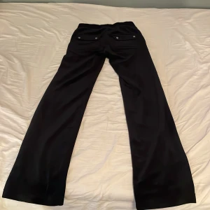 Svarta mjukisbyxor från Juicy Couture - Säljer ett par svarta mjukisbyxor från Juicy Couture i storlek XXS. Byxorna har en bekväm passform med snörning i midjan och praktiska fickor. Perfekta för en avslappnad stil. Knappast andvända och ser nästan nya ut 