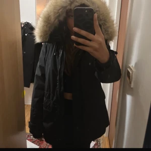 Svart parkajacka med pälskantad huva - Säljer en svart parkajacka från Zara  i storlek L. Jackan har en pälskantad huva och är perfekt för vintern. Den är i nytt skick med etikett kvar. Insidan är quiltad för extra värme och komfort. Perfekt för kalla dagar! ❄️