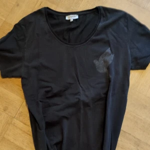 Svart t-shirt från Galagowear - Snygg svart t-shirt från Galagowear med ett diskret tryck av en fågel på framsidan och ett större logotryck på baksidan. Perfekt för en avslappnad stil.