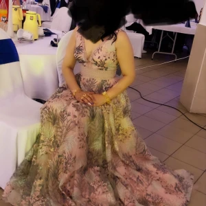 Blommig långklänning från Crystal Lane - Säljer en fantastisk blommig långklänning från Crystal Lane i storlek 36.. Klänningen har en vacker spetsdetalj och är ärmlös med en djup v-ringning. Perfekt för festliga tillfällen med sitt eleganta mönster och mjuka material.