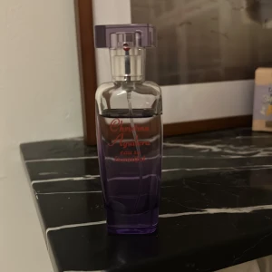 Parfym från Christina Aguilera - Säljer en elegant parfymflaska från Christina Aguilera. Flaskan är lila och har en stilren design med en genomskinlig kork. Perfekt för att ge en touch av glamour till din doftsamling. Passar både till vardags och fest!