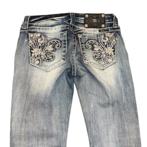 Miss Me Jeans - Snygga miss me jeans i ljusblå denim med coola broderade detaljer på bakfickorna. De har en klassisk femficksdesign och en låg midja. Perfekta för en avslappnad men stilren look. Passar både till vardags och fest!