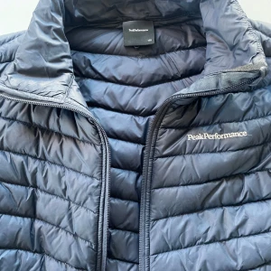 Täckjacka Peak Performance  - Marinblå tunnare täckjacka från Peak Performance. Använd men i mkt bra skick!          Stl 170. Helt intakt, hel och ren. Kan användas många år till! 