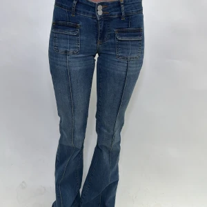 Blå bootcut jeans - Snygga blå bootcut jeans i mycket bra skick. De har en låg midja och coola fickdetaljer fram. Perfekta för både vardag och fest! Passar till allt från sneakers till klackar.