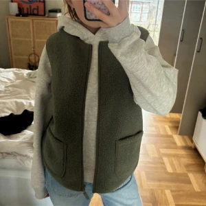 Olivgrön fleeceväst från Saint Tropez - Säljer en olivgrön fleeceväst från Saint Tropez i storlek M. Västen har en enkel design med dragkedja och två praktiska fickor framtill. Perfekt för lager-på-lager under höst och vår. Supermysig och lätt att matcha med olika outfits!