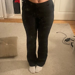 Svarta kostymbyxor - Säljer ett par stilrena svarta kostymbyxor i mycket bra skick. De är högmidjade med bootcut. Perfekta för både kontoret och mer formella tillfällen. Byxorna har en knapp och dragkedja framtill för enkel stängning. Har ett litet hål i fickan men det syns inte. 