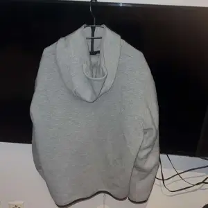 Säljer en grå hoodie från Nike i bra skick. Den har en dragkedja framtill och en cool svart detalj över bröstet. Perfekt för höst och vår, och den har en ficka på ärmen för extra stilpoäng. Superbekväm och passar till det mesta!