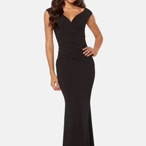 Svart långklänning med v-ringning - Elegant svart långklänning med v-ringad hals och ärmlös design. Perfekt för festliga tillfällen. Klänningen har en figurnära passform som framhäver silhuetten.