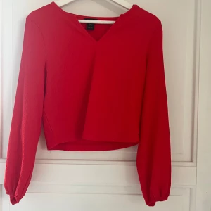 Röd blus med v-ringning - Snygg röd blus från Lindex med v-ringning och långa ärmar. Materialet har en texturerad yta som gör den mer elegant. Använd ca 2 ggr, så den är i väldigt bra skick! Storleken xs💗