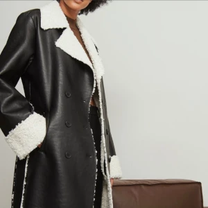 Lång Läderkappa - nyskick - Säljer min långa läderkappa med teddydetalj på insidan. Den är i nyskick. Köpt för 1400kr från NA-KD. Priset kan diskuteras👍🏼