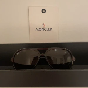 Rayban solglasögon  - Snygga svarta solglasögon från Ray-Ban i klassisk aviator-stil. Perfekta för både vardag och fest, med en stilren design som passar alla tillfällen. De har en robust metallram och mörka linser som skyddar mot solen. Ett måste för den stilmedvetna! Köpta för 1399 säljes för runt 499 (ge prisförslag)