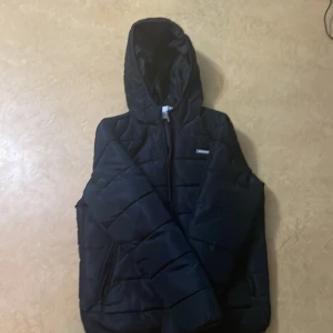 Svart pufferjacka från Jack & Jones - Säljer en svart pufferjacka från Jack & Jones i storlek M. Jackan är perfekt för höst och vinter med sin quiltade design och huva. Den har en dragkedja framtill och två praktiska fickor. använt i knappt 1 månad. Den har ett litet hål i sista bilden vilket man kan sy ihop eller alternativt kan jag sy den för en slant extra!
