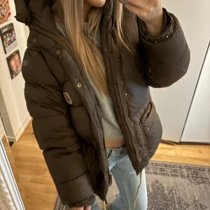 Brun dunjacka från Fjällräven - Säljer en supermysig brun dunjacka från Fjällräven.  Storlek xxxs o passar allt från xxxs till m beroende på hur man vill att den ska sitta. Perfekt för kalla vinterdagar och höstpromenader. Jackan är i bra skick med få defekter och håller dig varm och bekväm hela säsongen. Bästa jackan någonsin! Säljer ändast för att jag vill byta färg.