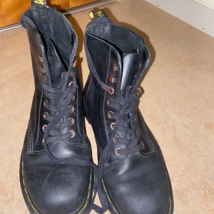 Dr. Martens  - Säljer ett par klassiska svarta Dr. Martens boots i bra skick. De har den ikoniska gula sömmen och är gjorda i slitstarkt skinn. Perfekta för både höst och vinter, med en robust sula och bekväm passform. Snörningen ger en cool look och de är lätta att matcha med olika outfits.  Säljer då inte är i min stil, köpte på Plick!