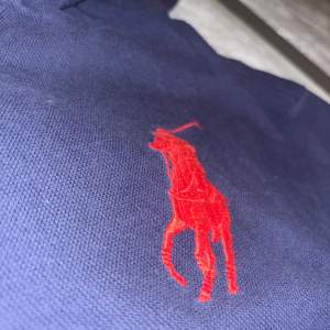 Säljer en äkta och snygg mörkblå pike hoodie från Ralph Lauren med röd insida i huvan. Den har ett stort rött nummer 3 på ärmen och den klassiska Ralph Lauren-loggan på bröstet. Perfekt för en avslappnad stil eller en sportig look. Passar både till vardags och lite finare tillfällen. Passformen är 14-15 år.