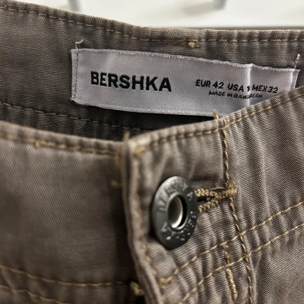 Säljer ett par snygga bruna cargobyxor från Bershka i storlek EUR 42. Byxorna har en loose passform med stora fickor på sidorna och en knappdetalj. Perfekta för både vardag, lite finare tillfällen och passar bra till höstgarderoben. Mid waist. Jeans & Byxor.