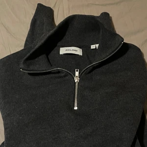 Mörkgrå tröja från Jack & Jones - Säljer en snygg mörkgrå tröja från Jack & Jones i storlek XS. Den har en dragkedja framtill och är perfekt för både höst och vinter. Tröjan är i mycket bra skick och passar till alla tillfällen. Perfekt för dig som gillar stilren design!