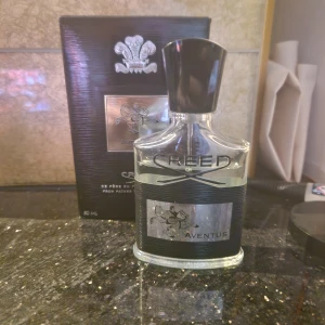 Creed Aventus parfym - Säljer en lyxig Creed Aventus parfym i en elegant glasflaska med svart och silver detaljer. Flaskan rymmer 50 ml och kommer med originalförpackning. Perfekt för den som vill ha en sofistikerad och tidlös doft. Passar både till vardags och speciella tillfällen. . Orginalpriset är också 2600 kr!!